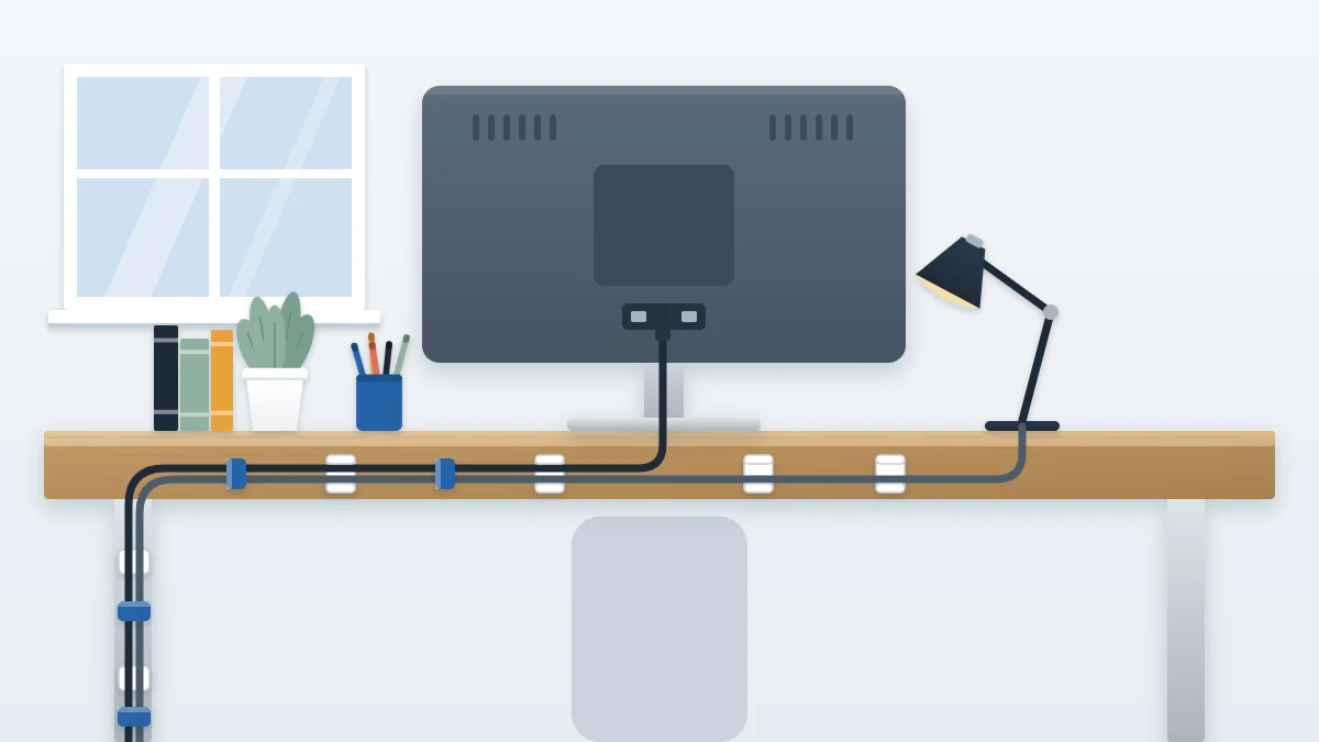 Back edge of a desk with a monitor cable and lamp cord gathered in soft fabric ties and guided through small clips in one line