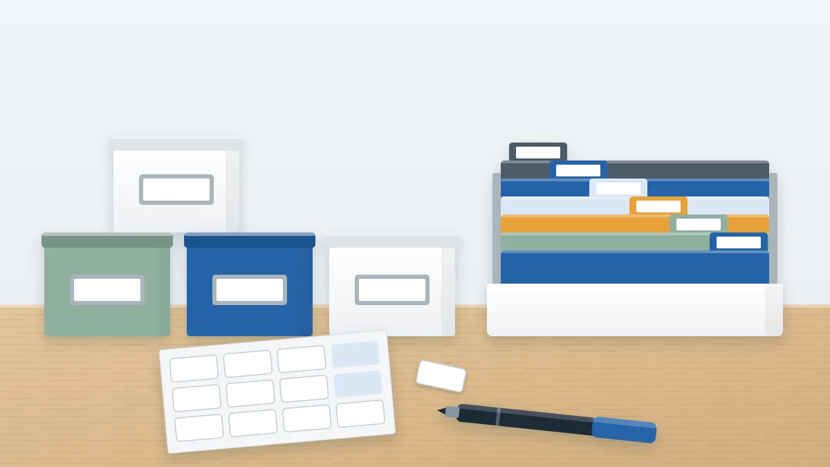 Three storage boxes and a row of file folders each with a blank white label in the same position, with a label sheet and marker in front